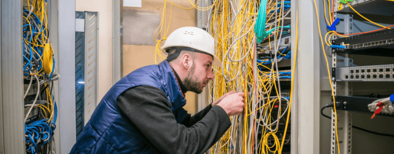 A man installs a network cable harness, focusing on efficient setup to minimize delays.